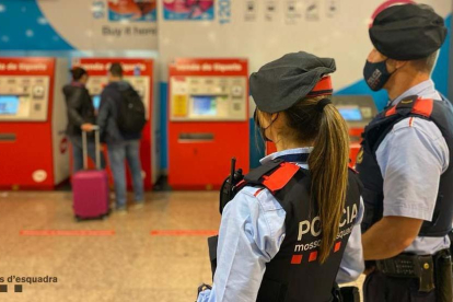 Dos agentes de los Mossos d'Esquadra a una estación del metro de Barcelona, con las máquinas expendedoras de billetes al fondo