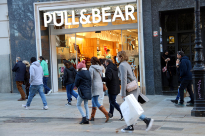 Compradors passen per davant d'una botiga Pull & Bear a Barcelona.