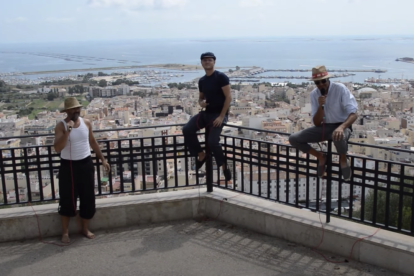Imatge del videoclip amb el tres músics i el municipi al fons.
