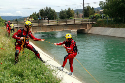 Dos bombers fent pràctiques de rescat aquàtic al canal de Gavet. Un bomber estira amb una corda a un altre que simulava haver caigut.