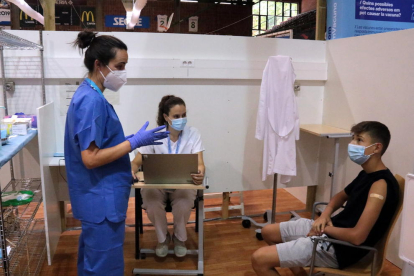 Una enfermera dando explicaciones a un joven que acaba de recibir la vacuna contra la covid-19 en el pabellón Onze de Setembre de Lleida.