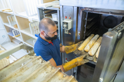 Noel Urbano, de la Pastisseria Noel, ubicada en la calle de Florenci Vives, poniendo en el horno unas barras de pan.