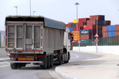 Un camión saliente de terminal de ICL al Puerto de Barcelona con contenedores al fondo.