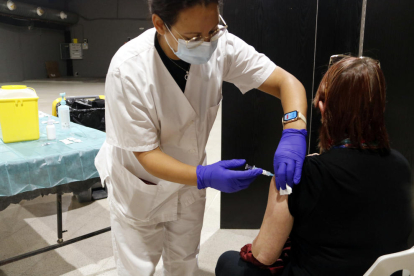 Una sanitària administrant una vacuna de la grip a una dona.