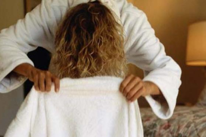 Imagen de una mujer secándose el pelo.