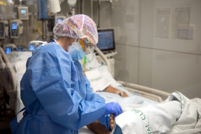 Una enfermera del Hospital Clínic hace un masaje en el pie a un paciente ingresado en el área de Cuidados intensivos (AVI, o UCI), durante la quinta oleada de la pandemia de la covid-19 en Cataluña.