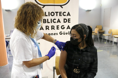 Una infermera posant una vacuna contra la covid-19 a una noia.
