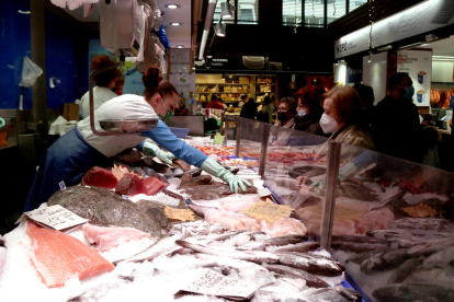 Vendedoras y clientes comprando para|por Navidad en un puesto de pescado|pez del Mercado Central de Tarragona.