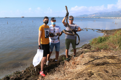 Tres voluntarios mostrando uno de los residuos recogidos durante la acción hecha a la bahía de los Alfacs.