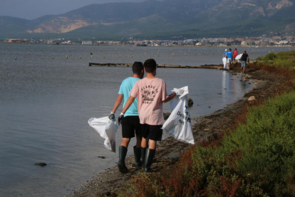 Dos voluntaris amb bosses netejant en l'acció feta a la badia dels Alfacs.