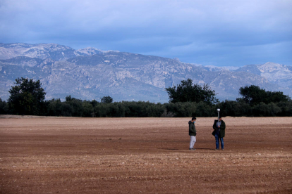 Los terrenos donde se proyecta la planta de compostaje en Santa Bàrbara con dos personas tomando medidas.