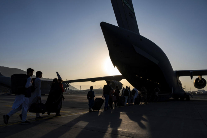 Un grup d'afganesos s'acosta a un avió de l'exèrcit dels Estats Units, a l'aeroport de Kabul, per ser evacuats.