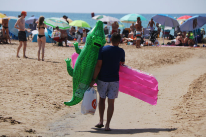 Un chico que se dirige a la playa de Salou (Tarragonès) con dos flotadores.
