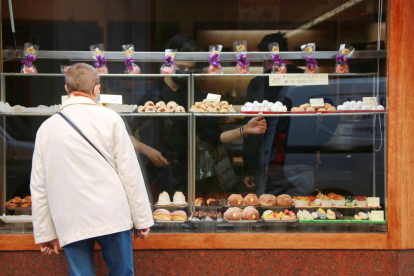 Una mujer que observa el escaparate de la Pastelería Palau de Tarragona, donde ya hay panellets.