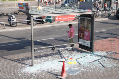 Una marquesina d'autobús pròxima a la plaça Espanya amb els vidres trencats.