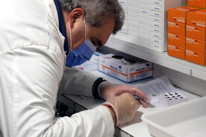 Plano corto de un farmacéutico analizando una muestra de un test de antígenos.