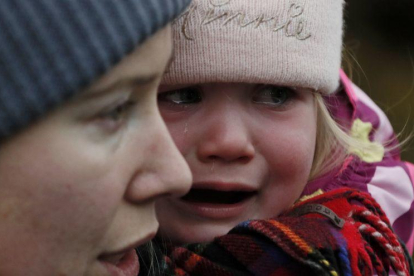 Un menor llora en brazos de su madre en la frontera de Ucrania con Rumania.