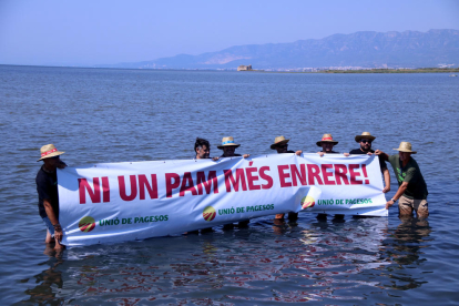 Membres d'Unió de pagesos subjectant una pancarta a la badia dels Alfacs.