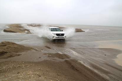 Un vehicle creua dins l'aigua un dels punts en què la barra del Trabucador s'ha trencat pel temporal.