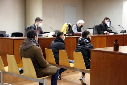 Els dos ciutadans acusats asseguts al davant i l'agent de la Guàrdia Urbana al darrere, a l'Audiència de Lleida.