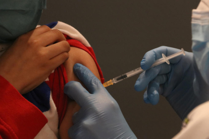 Pla detall d'un nen rebent una vacuna contra el coronavirus.