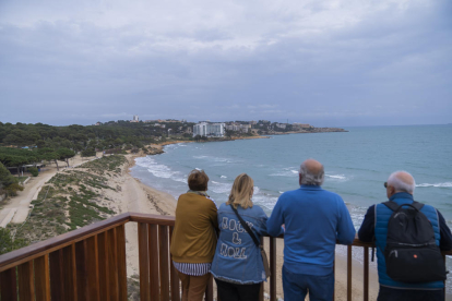 Varios vecinos mirando la playa Larga de Salou, afectada por la falta de arena.