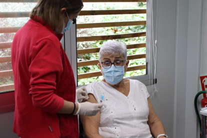 Una professional sanitària prepara el braç de la pacient abans de vacunar-la.