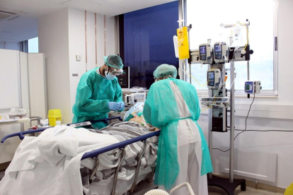Dos professionals mèdics atenent un pacient a l'UCI per covid-19.