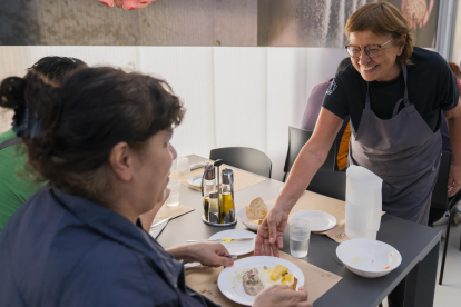 Roser, treballadora del Centre Social del Roser, i els seus companys serveixen el dinar als usuaris.