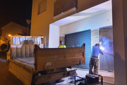 Dos operaris posant una porta antiocupes en un dels habitatges que han intentat ocupar.
