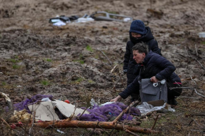 Una mujer con su hijo caminan en busca de comida en el lugar donde se asentó un campamento de soldados rusos en una autopista de Kiev.