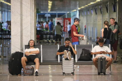 Turistes esperant en una terminal de l'aeroport del Prat.