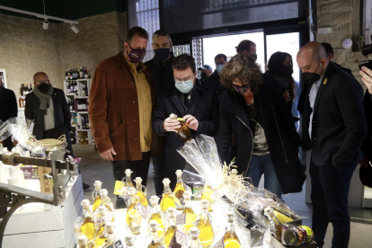 El president de la Generalitat, Pere Aragonès, i la consellera d'Acció Climàtica, Teresa Jordà, miren ampolles d'oli durant una visita a l'Agrobotiga de la Cooperativa d'Arbeca.