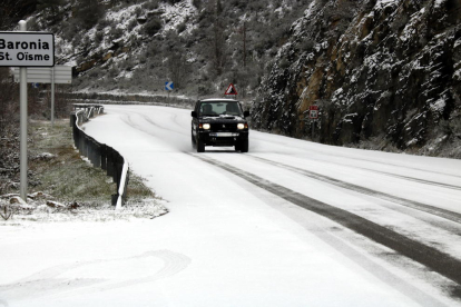 Un cotxe circulant per una carretera nevada.