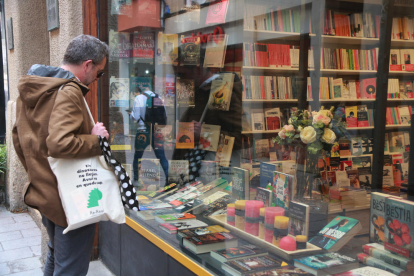 Un home mira l'aparador d'una llibreria de Reus el dia previ a la Diada de Sant Jordi.