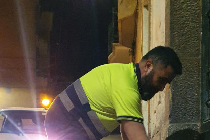 Un operario recoge un cubo de basura en el sistema puerta a puerta implantado en Flix.