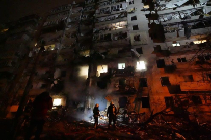 Dos bombers miren les destrosses provocades per un atac rus contra un bloc de 10 plantes de pisos a Kíev durant la matinada del 25 de febrer.