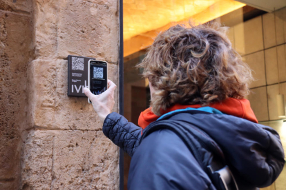 Una persona escaneando el QR de la nueva placa instalada en el exterior de la joyería 'Personal' de Tarragona.