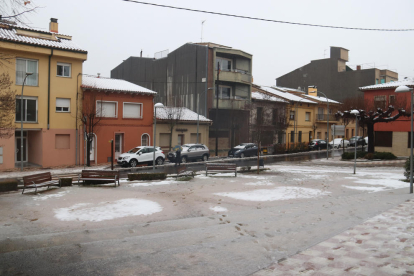 Diverses cases de Sant Hilari Sacalm enfarinades i una plaça amb la neu mig fosa per la pluja.