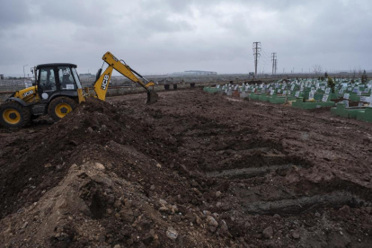 Una excavadora prepara lloc digs graves for victims of the earthquake at a cemetery in Diyarbakir