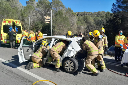 Imatge del moment que els Bombers ajuden a sortir a les persones atrapades dins del seu vehicle.