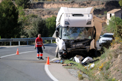 Un operari retira les restes del vehicle que han quedat davant del camió accidentat a Batea.