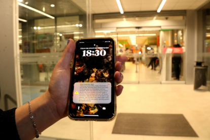 Una vecina muestra el mensaje recibido en el teléfono móvil para iniciar el simulacro a las puertas de un supermercado de La Canonja.