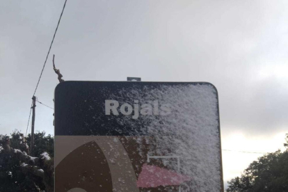 La senyal d'entrada a Rojals coberta per la neu.
