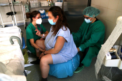 Una llevadora comprovant la situació d'una dona embarassada, minuts previs a donar a llum.