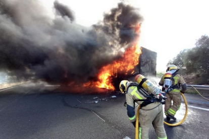 Dos bombers treballen en l'extinció d'un camió incendiat a l'AP-7, a Vilafranca del Penedès.