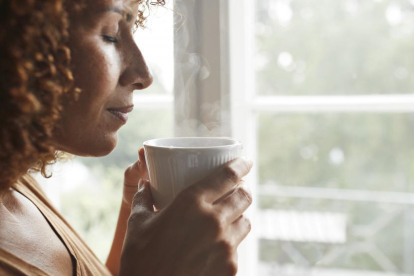 Una dona olora una tassa de cafè.