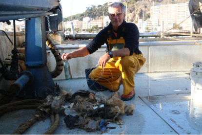 Un pescador mostrant algunes de les deixalles recollides a la seva embarcació.