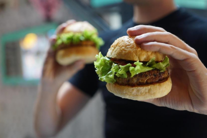 Un home sosté dos hamburgueses de carn.