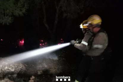 Dos bombers durant les tasques d'extinció de l'incendi en un barranc de
